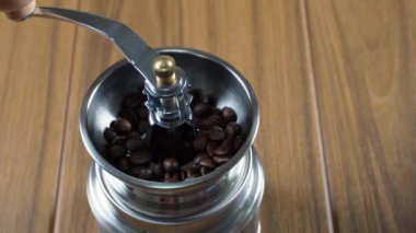 Carefully pouring coffee beans into a manual hand coffee grinder