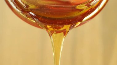 Close up shot of honey pouring out of glass jar. Health and beauty product sustainable lifestyle concept.
