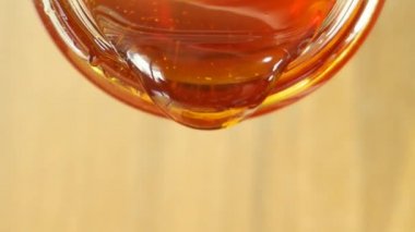 Close up shot of honey pouring out of glass jar. Health and beauty product sustainable lifestyle concept.