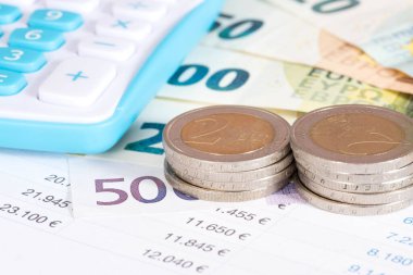 Avro banknotları ve madeni paralar, hesap makinesi ve farklı sayılar içeren tablolar