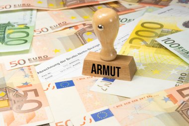 Avro banknotları ve madeni paraların üzerinde POVERTY yazısıyla yakın plan ahşap pul.