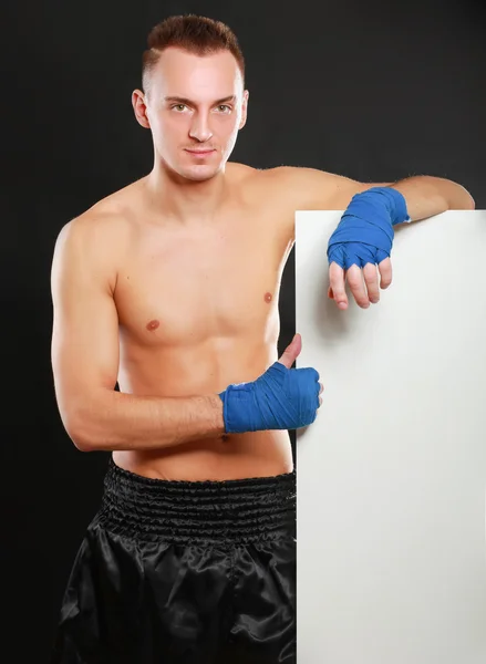 Junger gutaussehender Boxer, der in der Nähe von Bord steht, isoliert auf schwarzem Hintergrund — Stockfoto