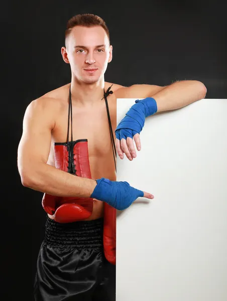 Young handsome boxer man standing near board , isolated on black background — Stock Photo, Image