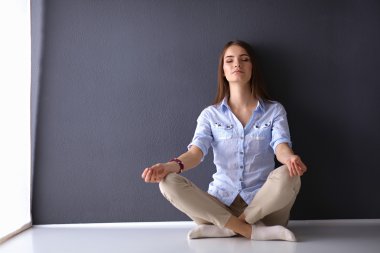 Genç Bayan duvara yakın katta oturan yoga yaparken