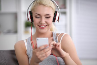 Evdeki genç ve güzel kadın kanepede oturup müzik dinliyor.