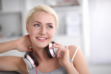 Evdeki genç ve güzel kadın kanepede oturup müzik dinliyor.