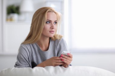 Genç ve güzel bir kadın odasında kanepede oturuyor.