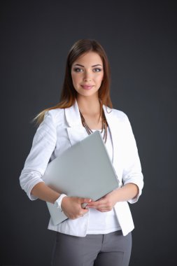 gri arka plan üzerinde izole bir laptop tutan genç kadın