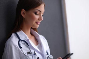 Genç bayan doktor yerde telefonunuzla oturuyor.
