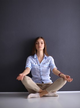 Genç Bayan duvara yakın katta oturan yoga yaparken