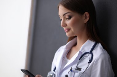 Genç bayan doktor yerde telefonunuzla oturuyor.