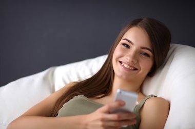 вродлива жінка у своїй вітальні, лежачи на дивані надсилання повідомлень