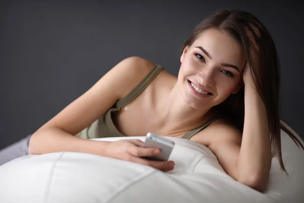 Pretty woman in her living room lying on the couch sending messages — Stock Photo, Image