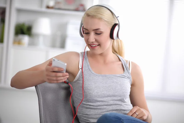 Young beautiful woman at home sitting on sofa and listening music — Stock Photo, Image