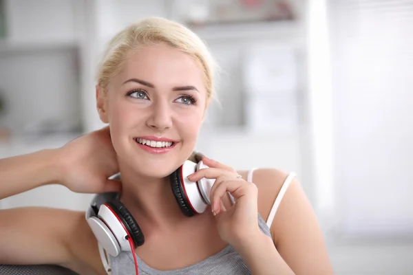 Jonge mooie vrouw thuis zitten op de bank en luisteren muziek — Stockfoto