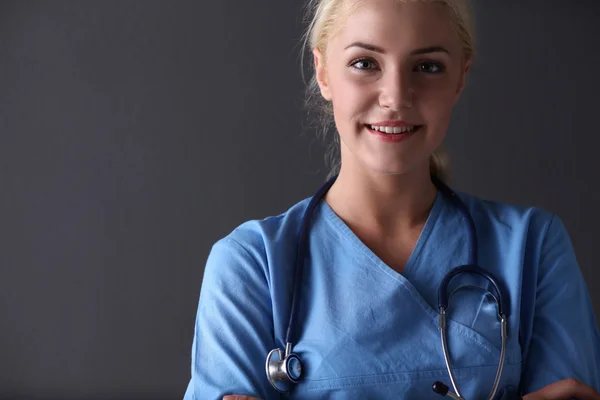 Молодая врач женщина со стетоскопом изолированы на сером фоне — стоковое фото