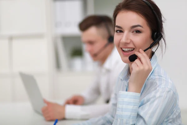 Mujer de negocios con auriculares sonriendo a la cámara en el centro de llamadas — Foto de Stock