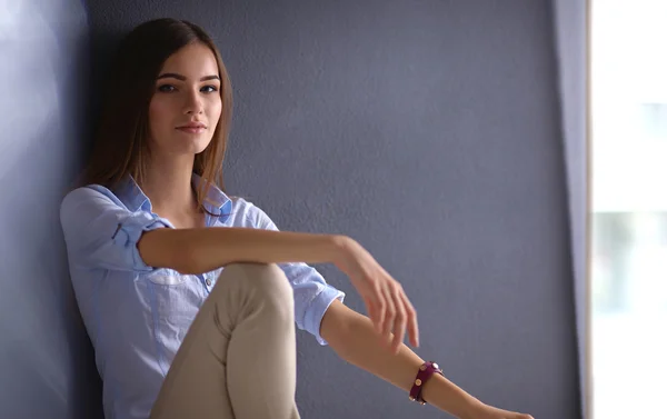 Jovem mulher sentada no chão perto da parede escura — Fotografia de Stock