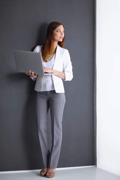 Jeune femme tenant un ordinateur portable, isolé sur fond gris — Photo