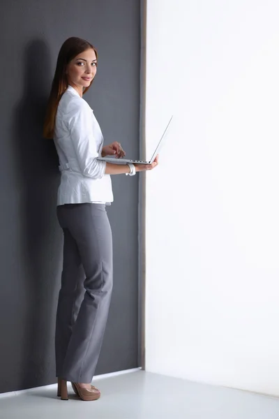 Młoda kobieta trzyma laptopa, na białym tle na szarym tle — Zdjęcie stockowe