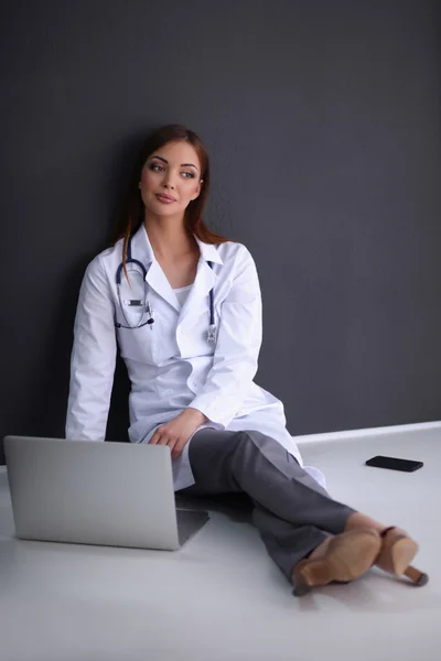 Doctor sentado en el suelo cerca de la pared con el ordenador portátil — Foto de Stock