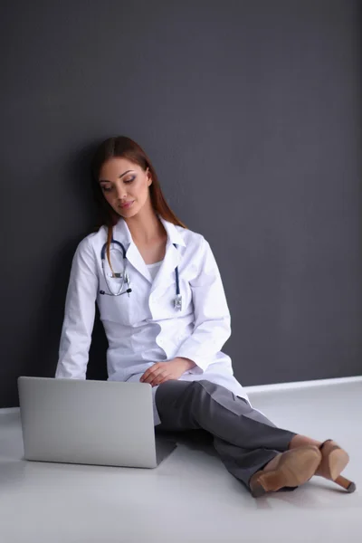 Doctor sitting on the floor near wall  with laptop — Stock Photo, Image