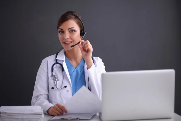 Doctor wearing headset sitting behind a desk with laptop — Stock Photo, Image