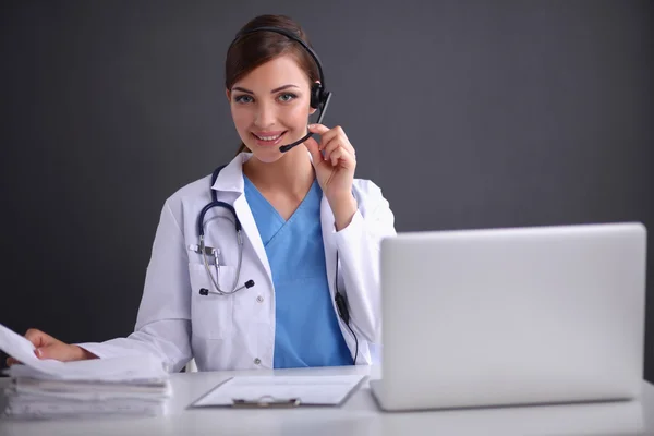 Médecin portant un casque assis derrière un bureau avec ordinateur portable — Photo