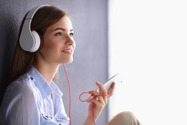 Smiling girl with headphones sitting on the floor — Stock Photo, Image