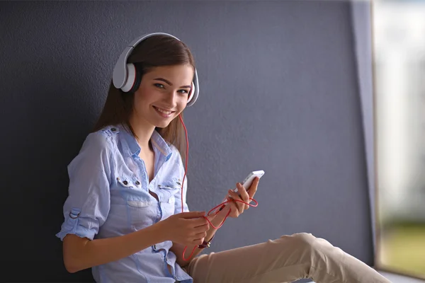 Lachende meisje met hoofdtelefoon zittend op de vloer — Stockfoto