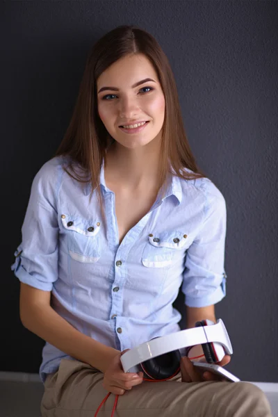 Chica sonriente con auriculares sentados en el suelo — Foto de Stock