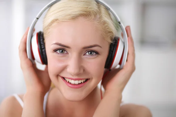 Young beautiful woman at home sitting on sofa and listening mus — Stock Photo, Image