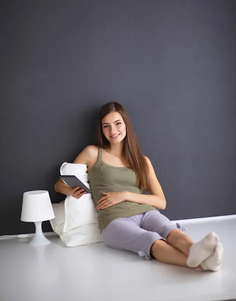 Pretty brunette woman sitting on the floor with a pillow and pl — Stock Photo, Image