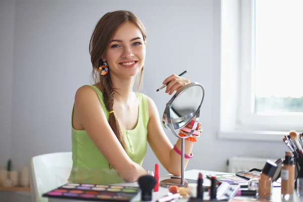 Joven hermosa mujer haciendo maquillaje cerca del espejo — Foto de Stock