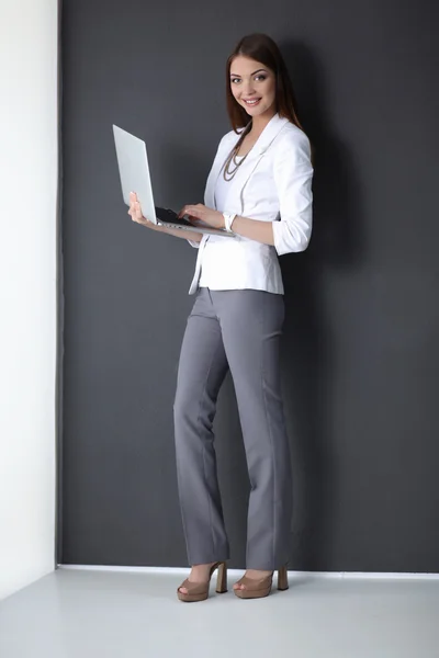 Young woman holding a laptop, isolated on grey background — Stock Photo, Image