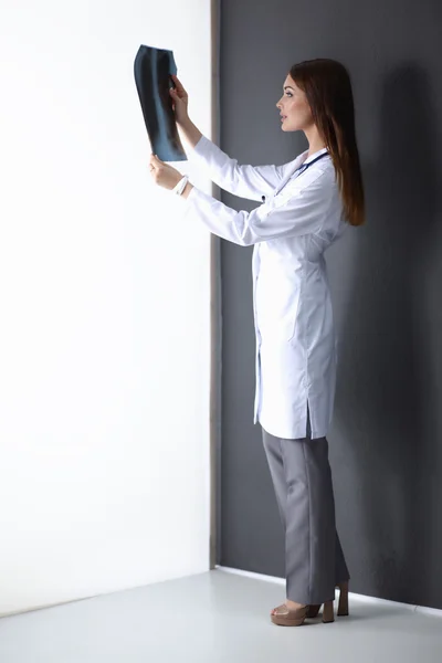 Doctora con imagen de rayos X de pie cerca de la pared gris — Foto de Stock