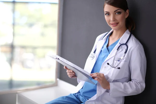 Krankenschwester hält Ordner in der Hand und macht Notizen - isoliert auf grauem Hintergrund — Stockfoto