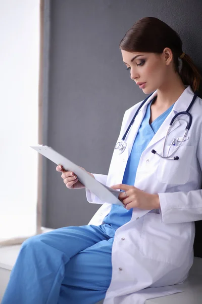 Krankenschwester hält Ordner in der Hand und macht Notizen - isoliert auf grauem Hintergrund — Stockfoto