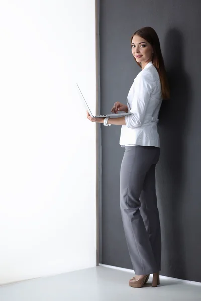 Jonge vrouw met een laptop, geïsoleerd op grijze achtergrond — Stockfoto
