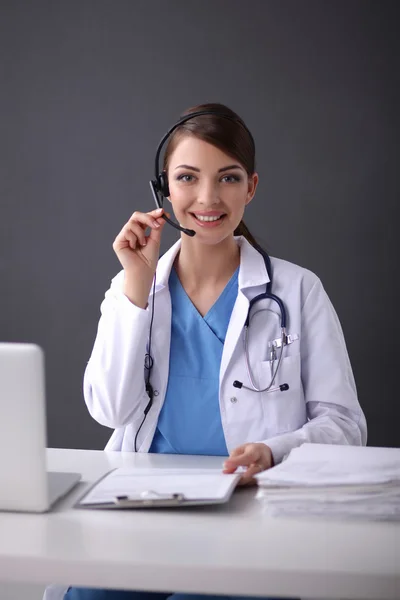 Doctor wearing headset sitting behind a desk with laptop — Stock Photo, Image