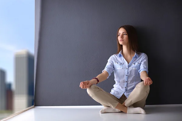 Mujer joven sentada en el suelo cerca de la pared, haciendo yoga —  Fotos de Stock