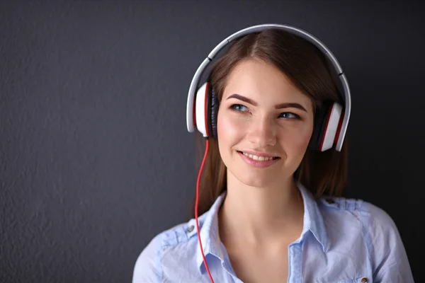 Menina sorridente com fones de ouvido isolados em fundo cinza — Fotografia de Stock