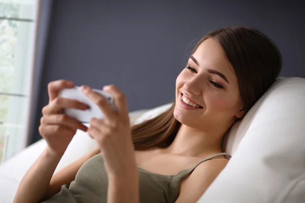 Mooie vrouw in haar woonkamer liggend op de bank verzenden van berichten — Stockfoto