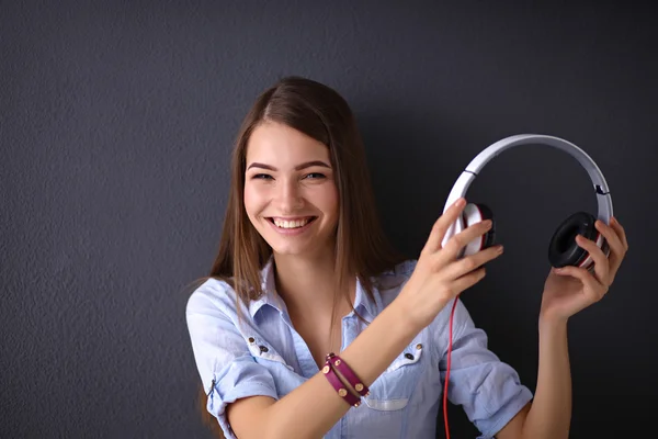 Усміхнена дівчина з навушниками ізольована на сірому фоні — стокове фото