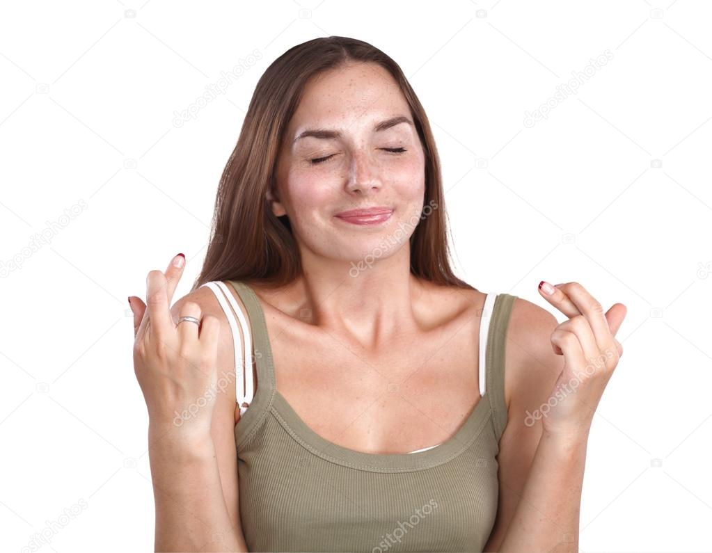 Portrait of woman crossing fingers against white background.