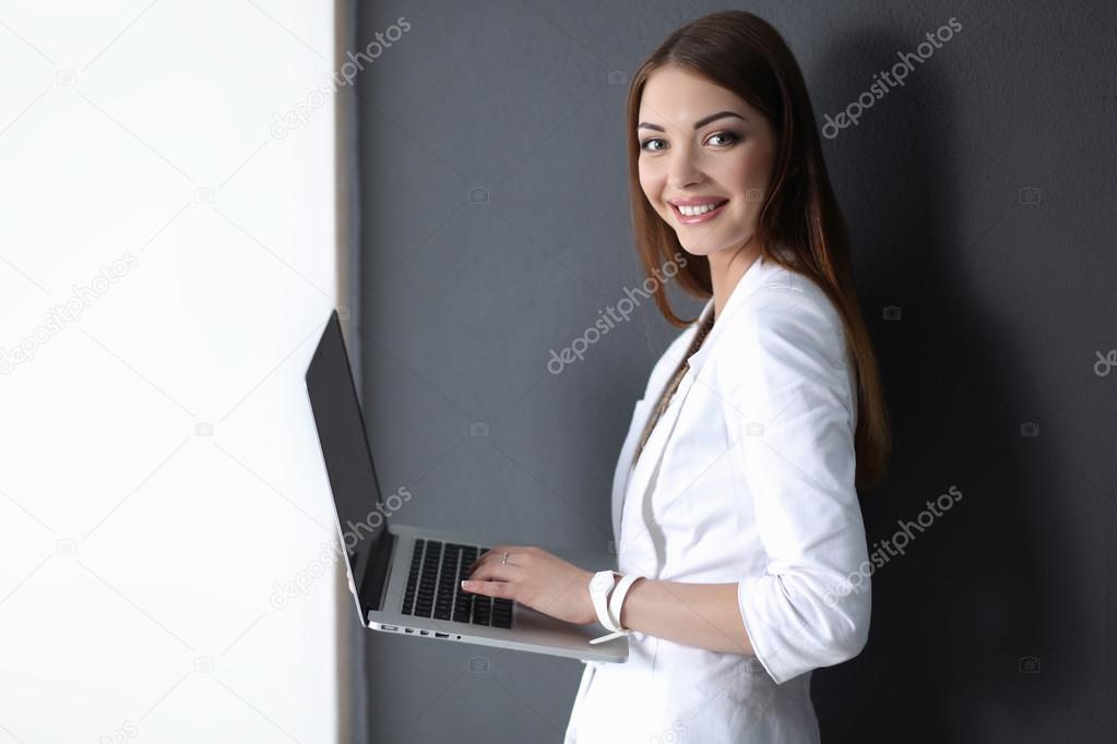 Young woman holding a laptop, isolated on grey background