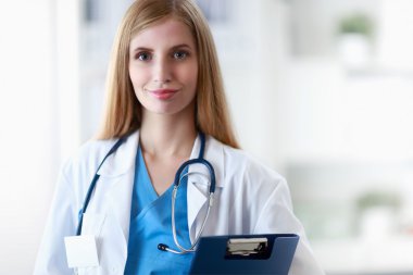 Hastane koridorunda klasörlü kadın doktor portresi.
