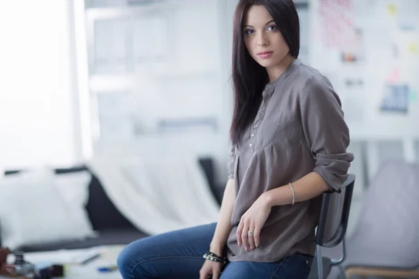 Piękna młoda kobieta siedzi na krześle w studio — Zdjęcie stockowe