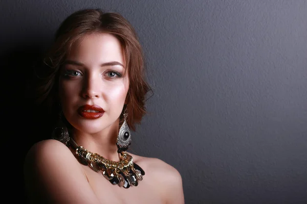 Young beautiful brunette woman in ear-rings, beads — Stock Photo, Image