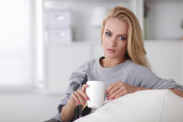 Jovem mulher bonita com uma xícara no sofá em casa — Fotografia de Stock